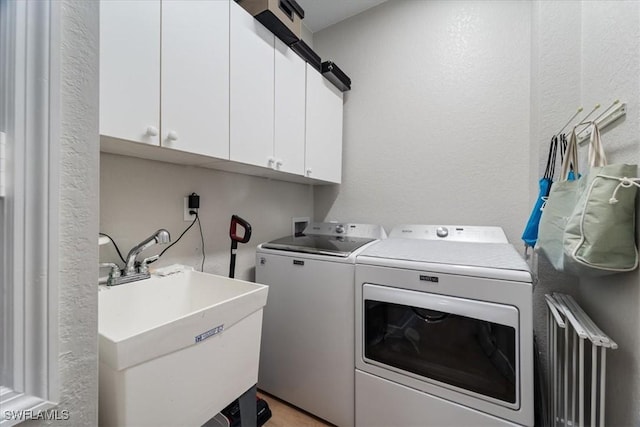 laundry room featuring a textured wall, separate washer and dryer, a sink, and cabinet space