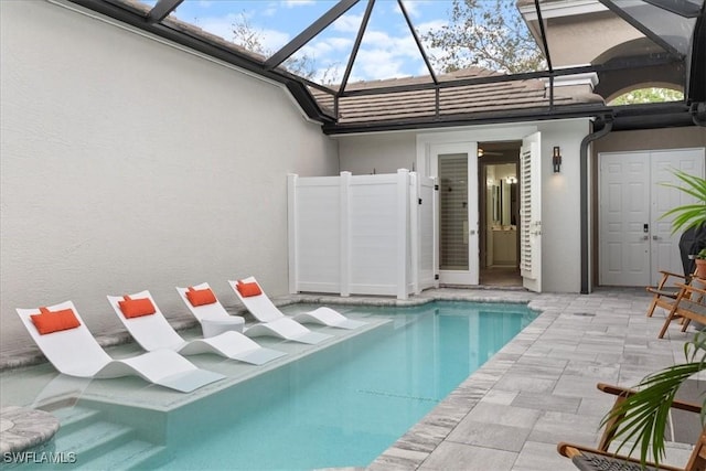 outdoor pool with glass enclosure and a patio area