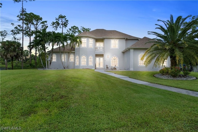 view of front of property with stucco siding, a front yard, and french doors