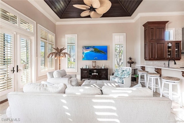 living area featuring a tray ceiling, wooden ceiling, a ceiling fan, and crown molding