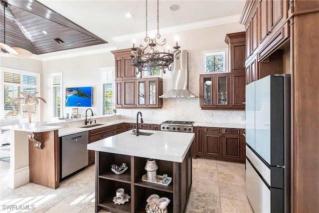 kitchen featuring appliances with stainless steel finishes, a sink, wall chimney range hood, and a peninsula