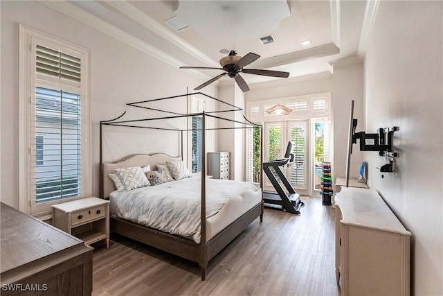 bedroom featuring visible vents, ornamental molding, access to exterior, a tray ceiling, and light wood-type flooring