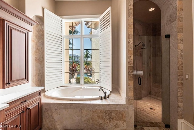 bathroom featuring a shower stall, vanity, and a bath