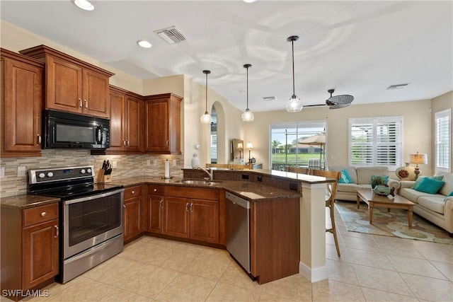 kitchen featuring visible vents, appliances with stainless steel finishes, brown cabinets, a breakfast bar area, and open floor plan