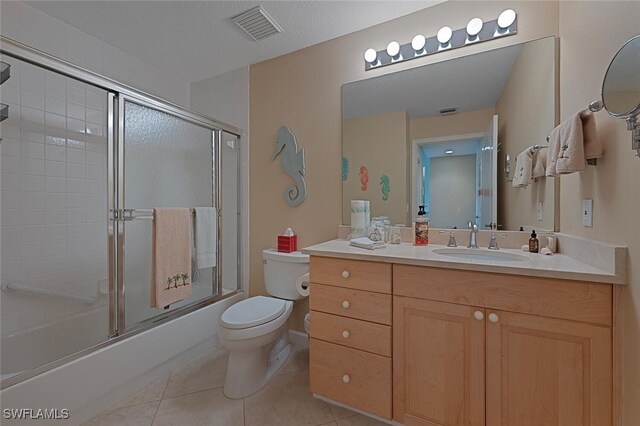 bathroom featuring visible vents, toilet, tile patterned floors, combined bath / shower with glass door, and vanity