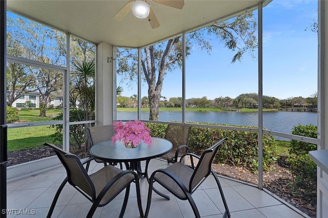 sunroom featuring a ceiling fan and a water view