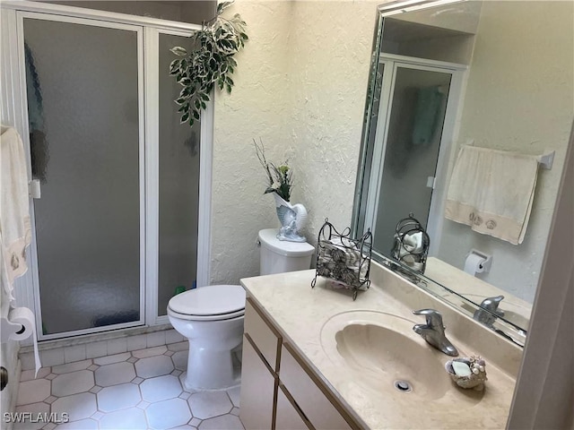 bathroom with a stall shower, a textured wall, vanity, and toilet