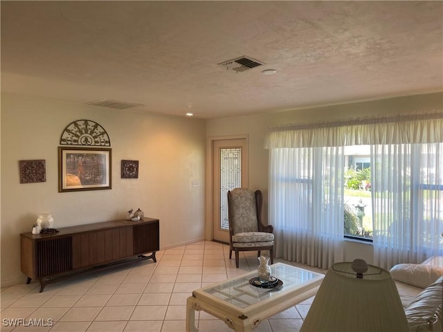 living room featuring light tile patterned floors, a textured ceiling, and visible vents