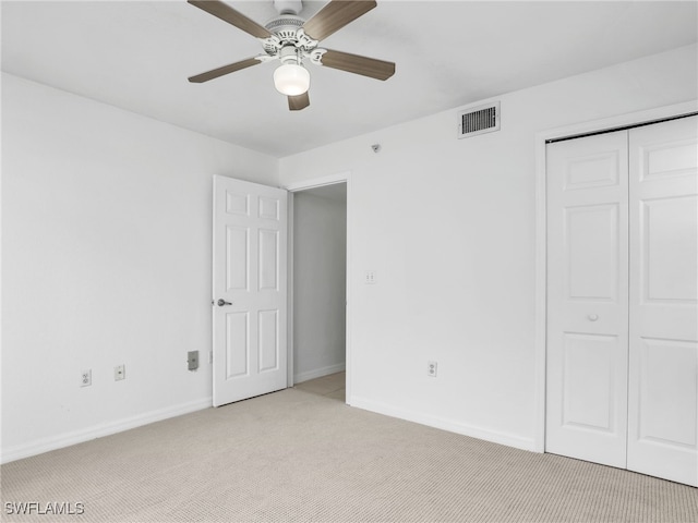 unfurnished bedroom featuring light carpet, a ceiling fan, visible vents, baseboards, and a closet