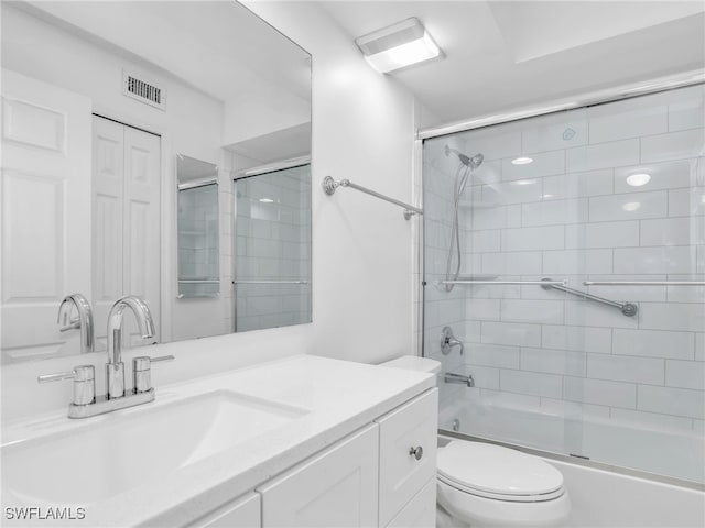 bathroom featuring toilet, visible vents, combined bath / shower with glass door, and vanity