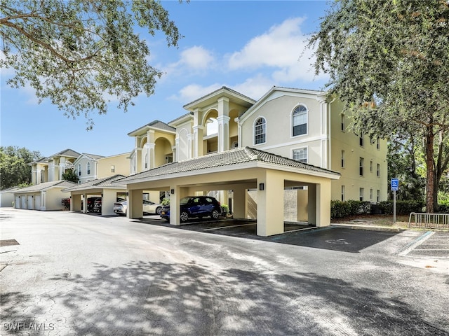 exterior space featuring covered parking, a tiled roof, and stucco siding