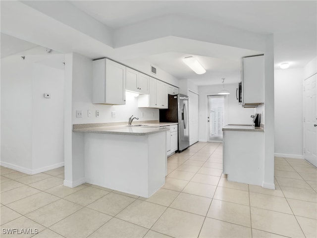 kitchen with light tile patterned floors, stainless steel appliances, light countertops, white cabinetry, and a sink