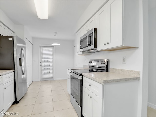 kitchen with pendant lighting, light tile patterned floors, appliances with stainless steel finishes, white cabinets, and baseboards