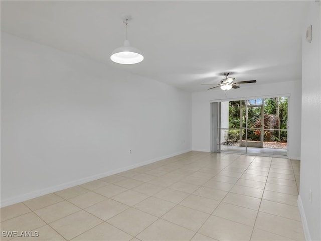 spare room featuring light tile patterned flooring, a ceiling fan, and baseboards