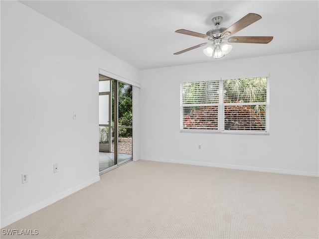 carpeted empty room with a ceiling fan and baseboards