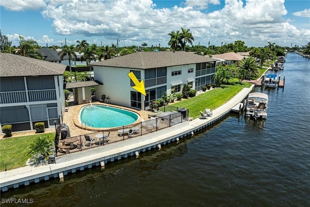 rear view of house with a fenced in pool, a yard, a water view, a sunroom, and a patio area