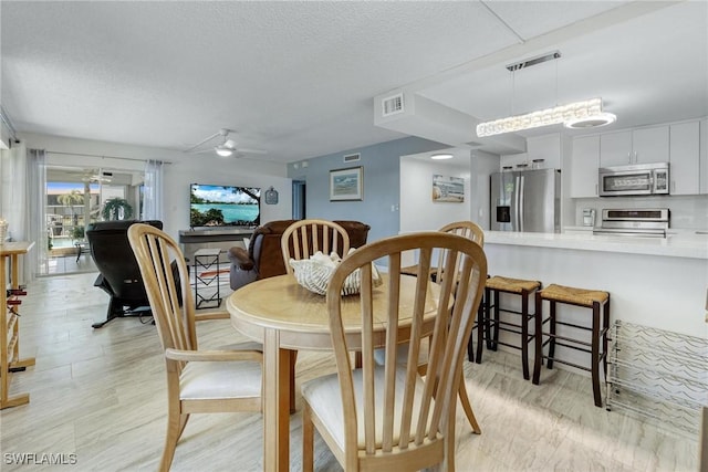 dining area featuring ceiling fan, visible vents, and a textured ceiling