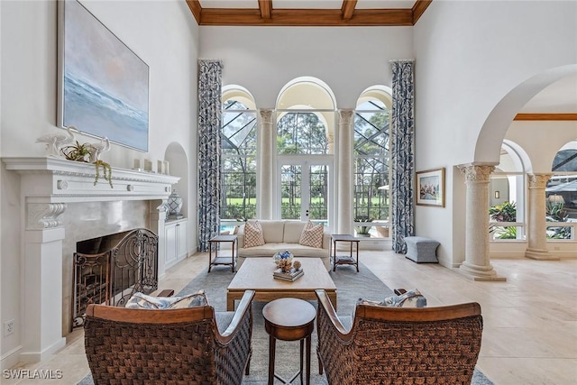 interior space with a fireplace, a wealth of natural light, a high ceiling, ornamental molding, and ornate columns