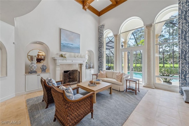 sitting room featuring light tile patterned flooring, a high ceiling, a premium fireplace, baseboards, and ornate columns