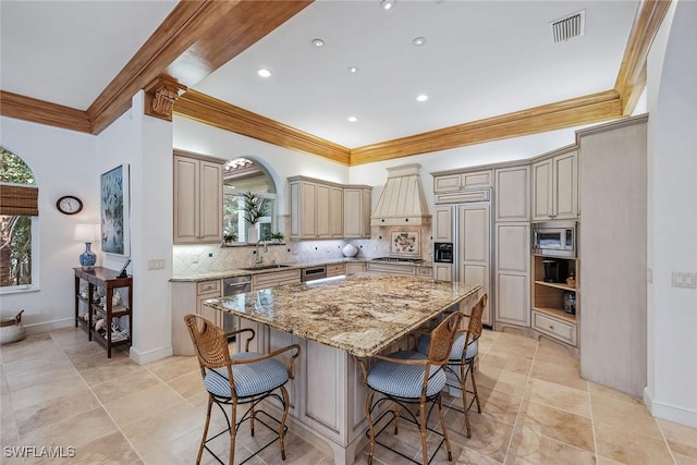 kitchen featuring appliances with stainless steel finishes, a center island, a sink, premium range hood, and backsplash