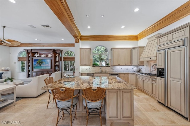 kitchen featuring paneled built in refrigerator, premium range hood, a breakfast bar, a sink, and open floor plan