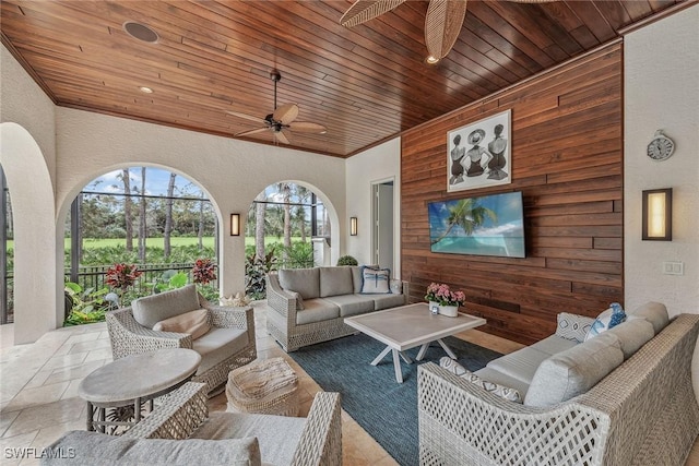 interior space featuring wooden walls, a textured wall, a sunroom, wood ceiling, and ceiling fan