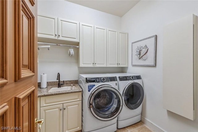 washroom with cabinet space, light tile patterned floors, baseboards, washing machine and clothes dryer, and a sink