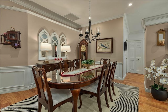 dining area featuring light wood-type flooring, wainscoting, and visible vents