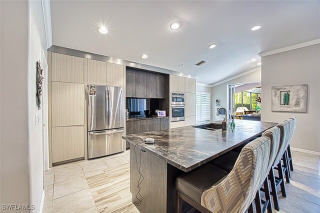 kitchen with visible vents, modern cabinets, a breakfast bar area, stainless steel appliances, and a sink