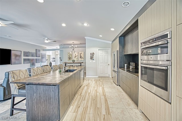 kitchen featuring ceiling fan, a breakfast bar, a sink, and appliances with stainless steel finishes