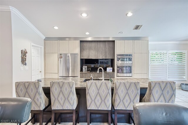 kitchen featuring visible vents, modern cabinets, appliances with stainless steel finishes, a kitchen breakfast bar, and crown molding