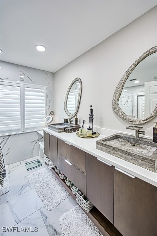 bathroom with recessed lighting, marble finish floor, a sink, and double vanity