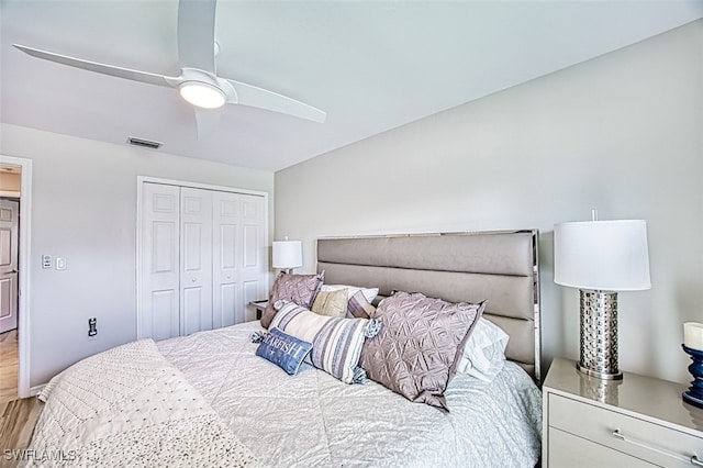 bedroom featuring a ceiling fan, a closet, visible vents, and wood finished floors