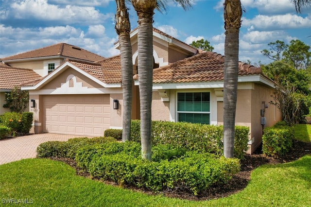 view of front of house with a garage, a tiled roof, decorative driveway, and stucco siding