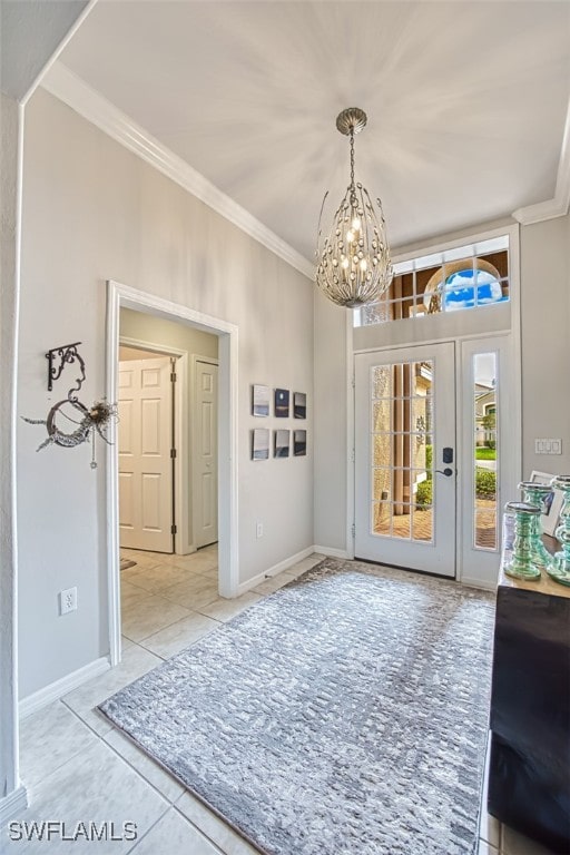 entryway with a notable chandelier, baseboards, tile patterned floors, and crown molding