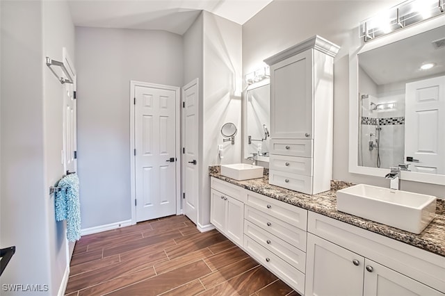 full bathroom with wood tiled floor, visible vents, a tile shower, and a sink