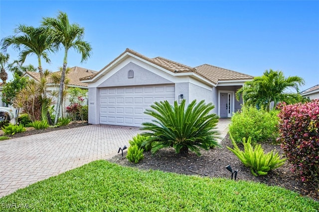 view of front of house featuring a garage, decorative driveway, a tile roof, and stucco siding