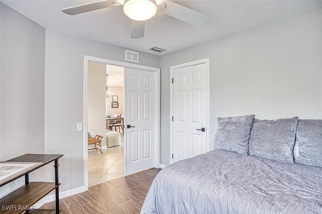 bedroom featuring baseboards, a ceiling fan, visible vents, and wood tiled floor