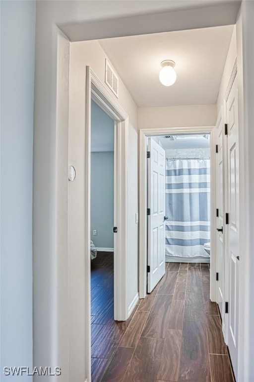 hallway with wood tiled floor, visible vents, and baseboards