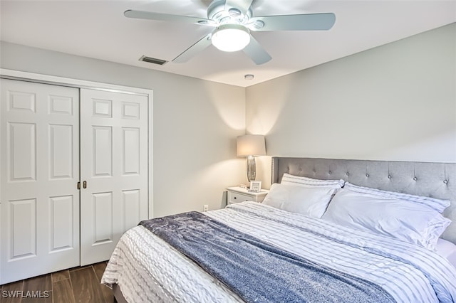 bedroom with ceiling fan, visible vents, dark wood finished floors, and a closet