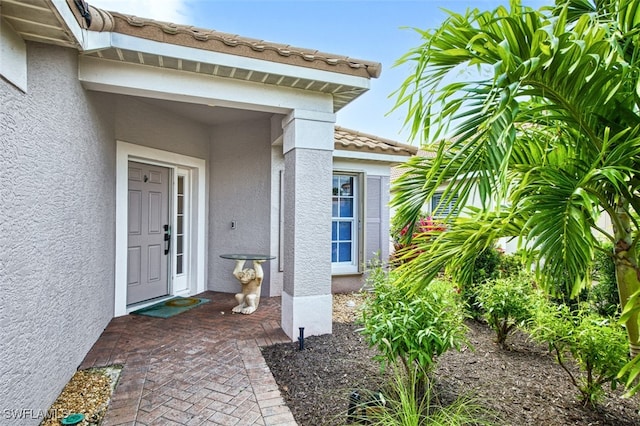 doorway to property featuring a tiled roof and stucco siding