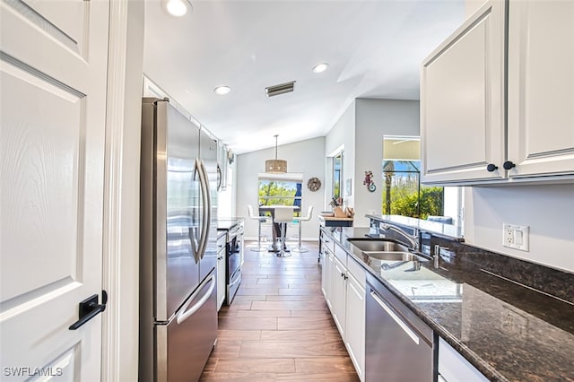 kitchen with lofted ceiling, a sink, visible vents, white cabinets, and appliances with stainless steel finishes