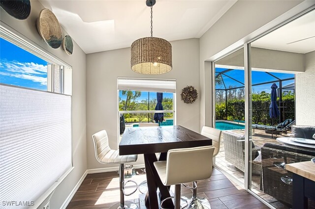 dining room featuring dark wood-style flooring, a sunroom, and baseboards