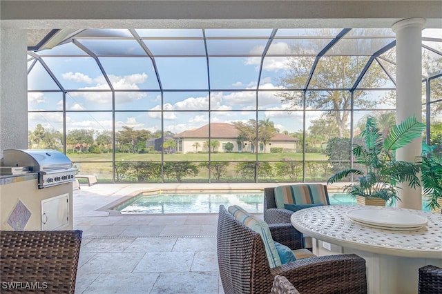 outdoor pool featuring glass enclosure, exterior kitchen, a patio area, and a grill