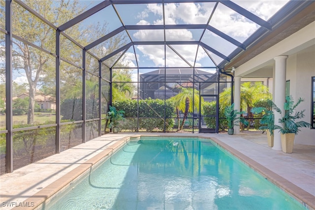 outdoor pool featuring glass enclosure and a patio area