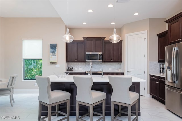 kitchen with stainless steel appliances, light countertops, dark brown cabinets, and a kitchen bar