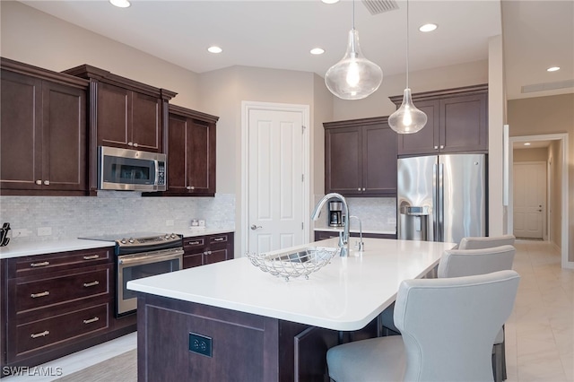 kitchen featuring light countertops, appliances with stainless steel finishes, a kitchen bar, and a sink