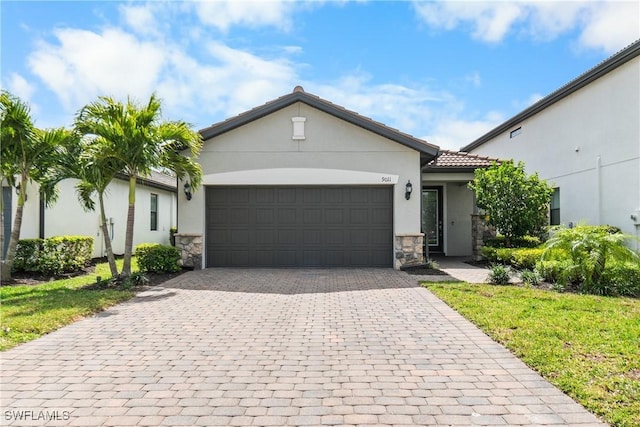 view of front of house with stone siding, a tile roof, an attached garage, decorative driveway, and stucco siding