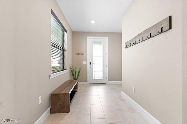 doorway to outside with light tile patterned flooring and baseboards