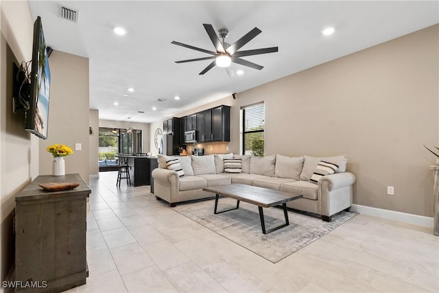 living room with light tile patterned floors, visible vents, baseboards, ceiling fan with notable chandelier, and recessed lighting